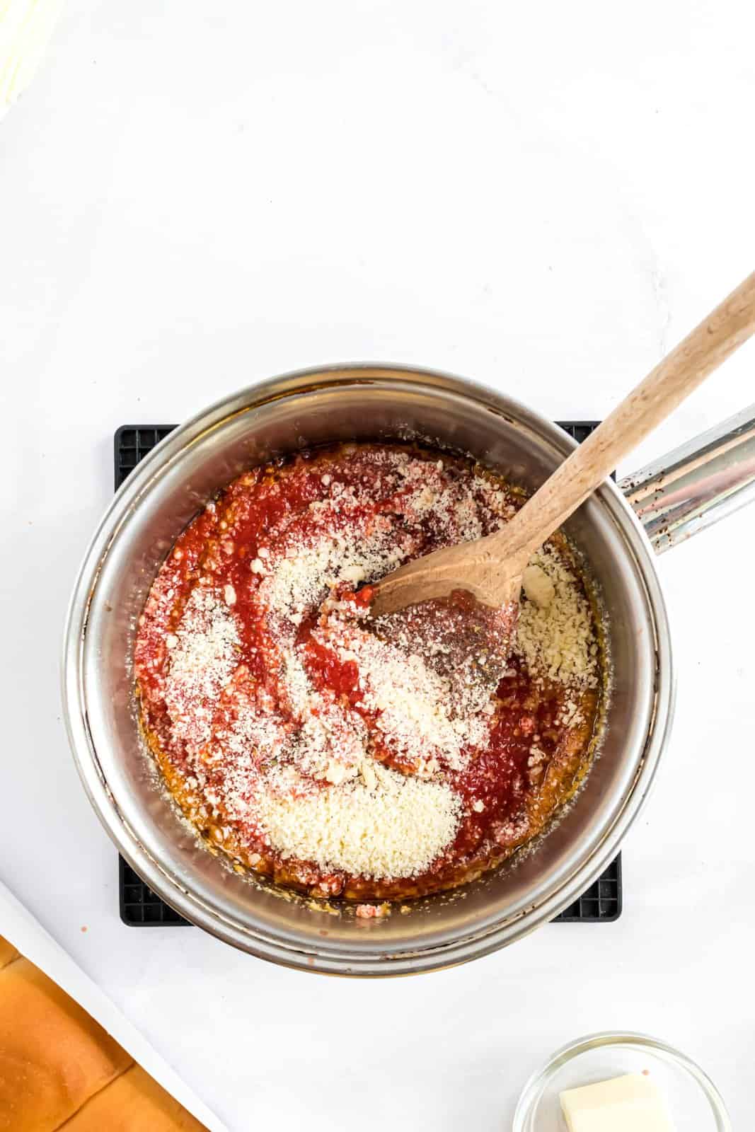 A saucepan with olive oil, pepperoni, tomato, basil, salt, pepper, cheese, and garlic.