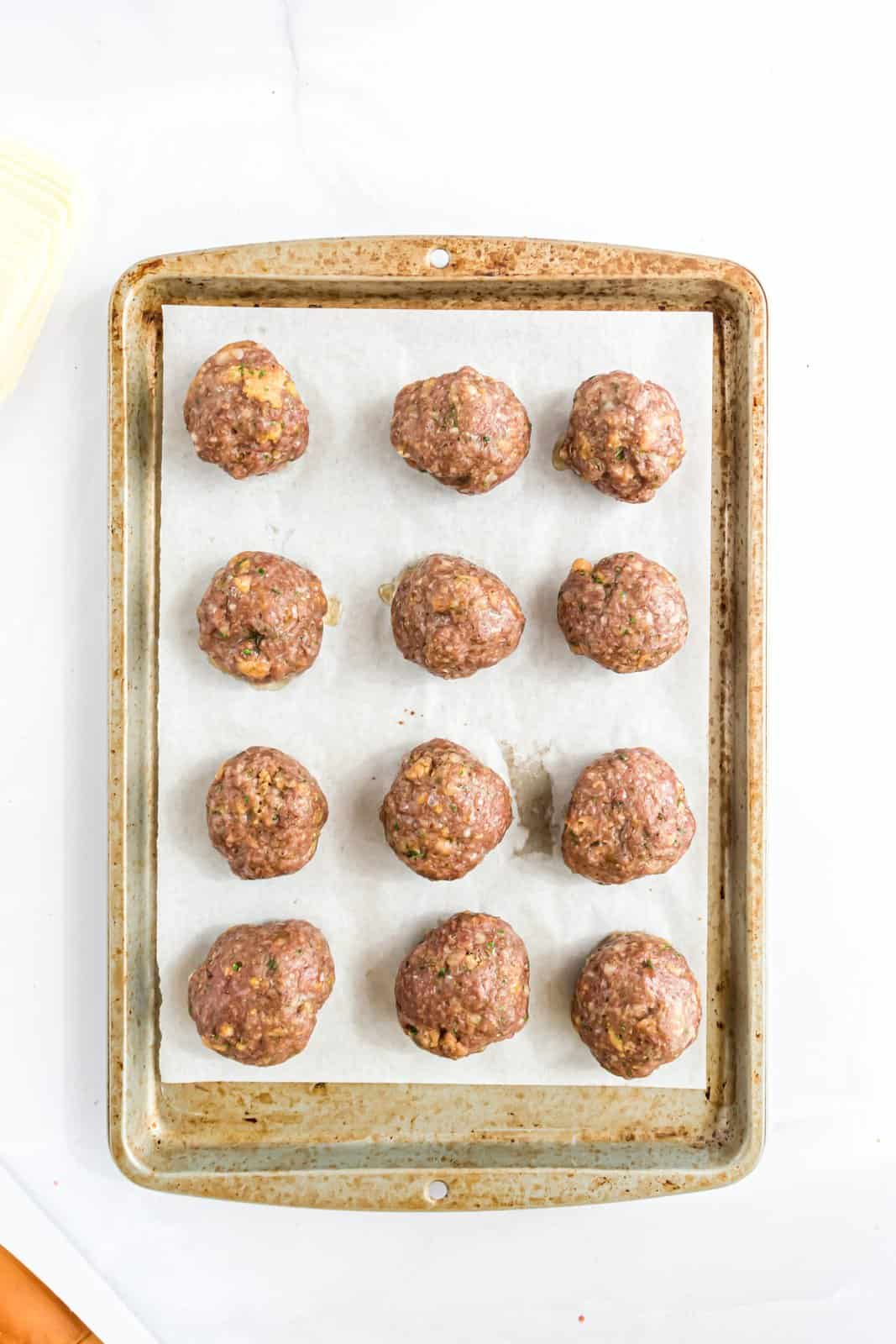Homemade baked meatballs on a baking sheet.