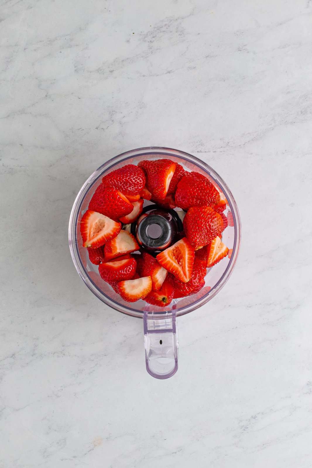 Food processor with strawberries in it. 