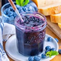 A small plate with a jar of homemade blueberry jam.