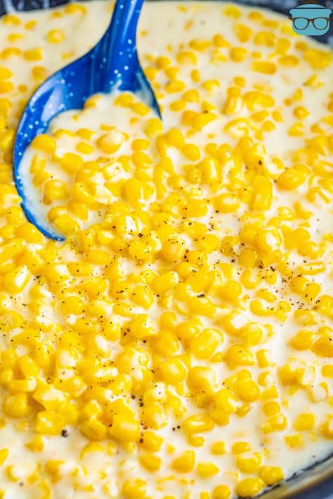 A blue spoon holding some creamed corn.