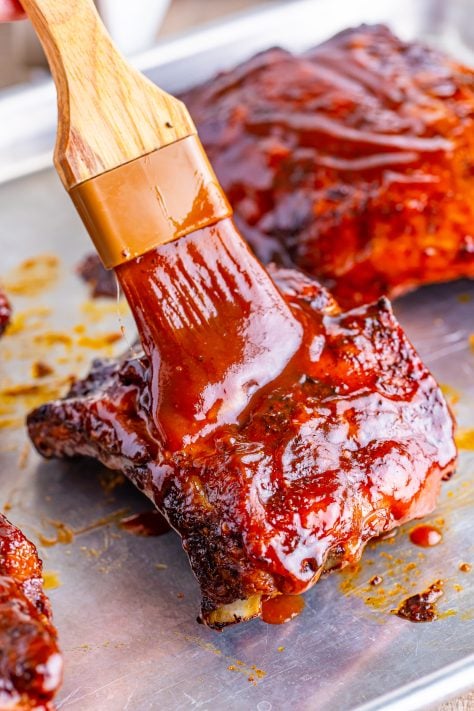 brushing BBQ sauce on the cooked ribs.