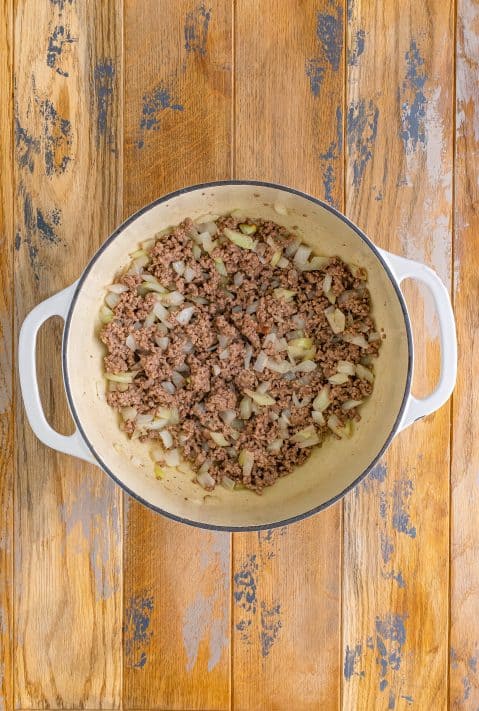 Cooked ground beef, onion, and bacon in a skillet.