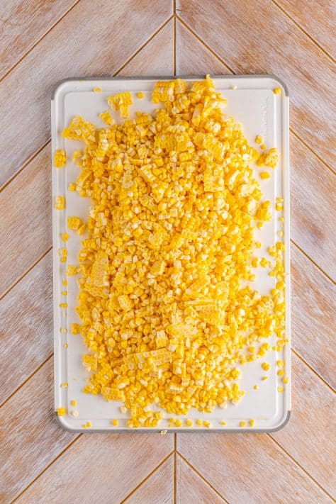 A cutting board with corn kernels.