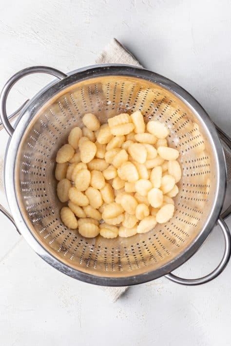 Cooked gnocchi in a strainer.