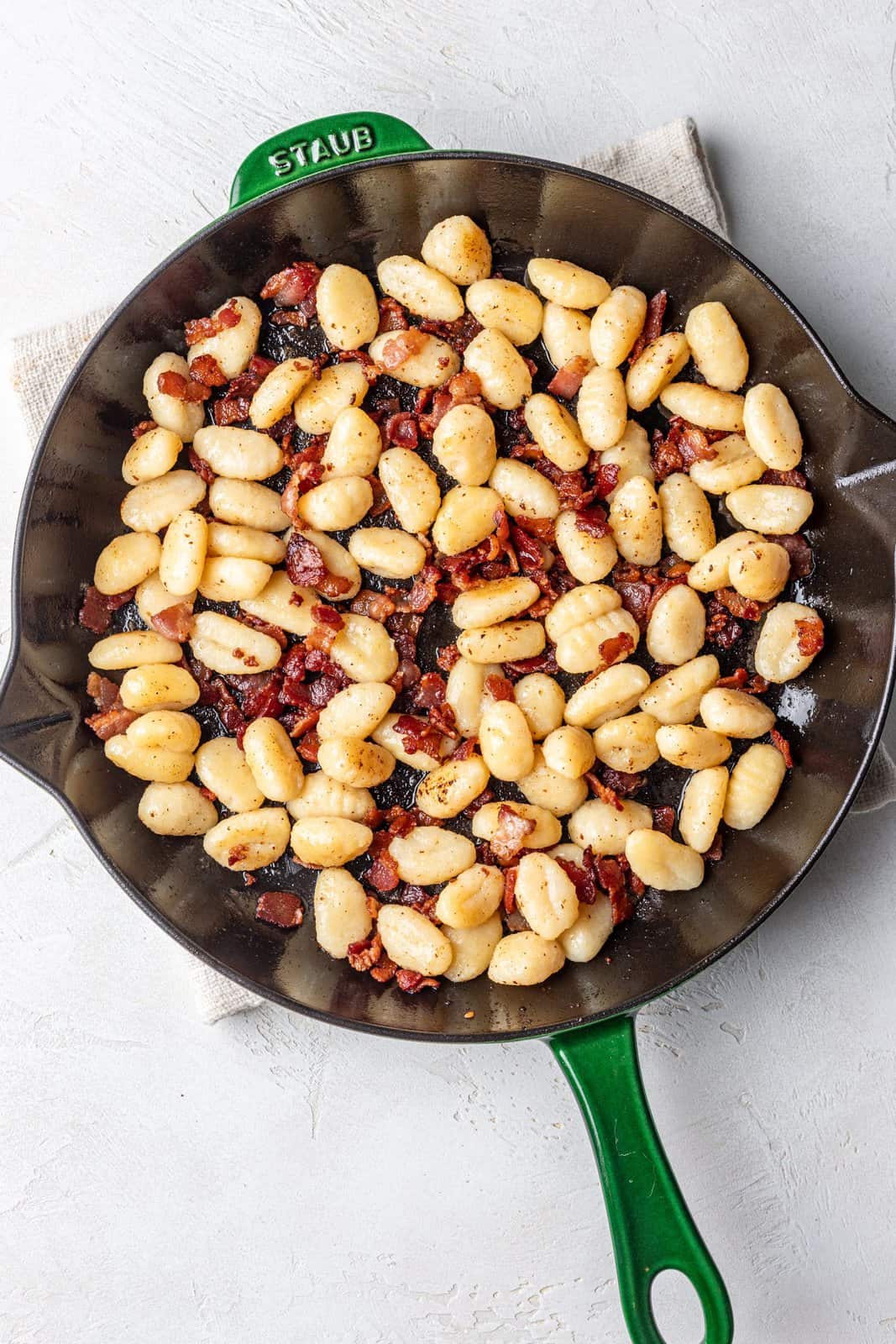 Gnocchi and bacon in a cast iron skillet.