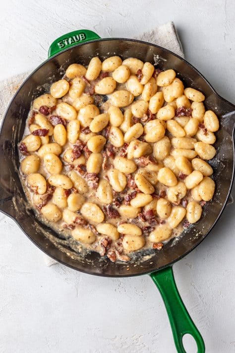 Gnocchi, bacon and tempered eggs in a skillet.