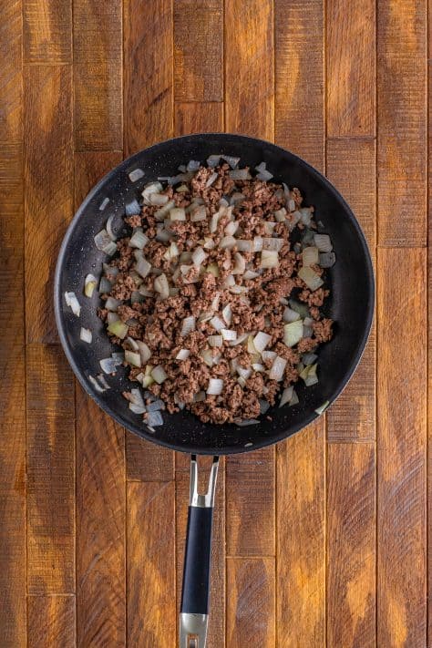 A skillet with ground beef and onion.