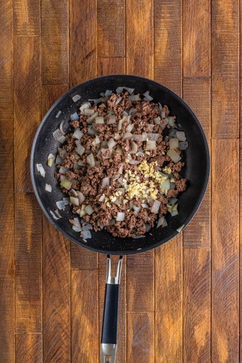 A skillet with ground beef, onion, and garlic.