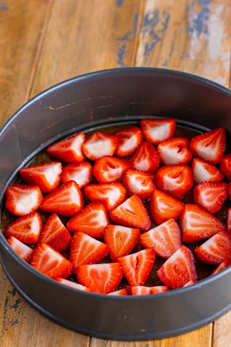 Sliced strawberries on top of the brown sugar butter mixture in a springform pan.