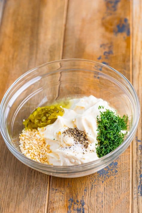 A mixing bowl with mayo, minced garlic, dill, sweet pickle relish, salt and pepper.