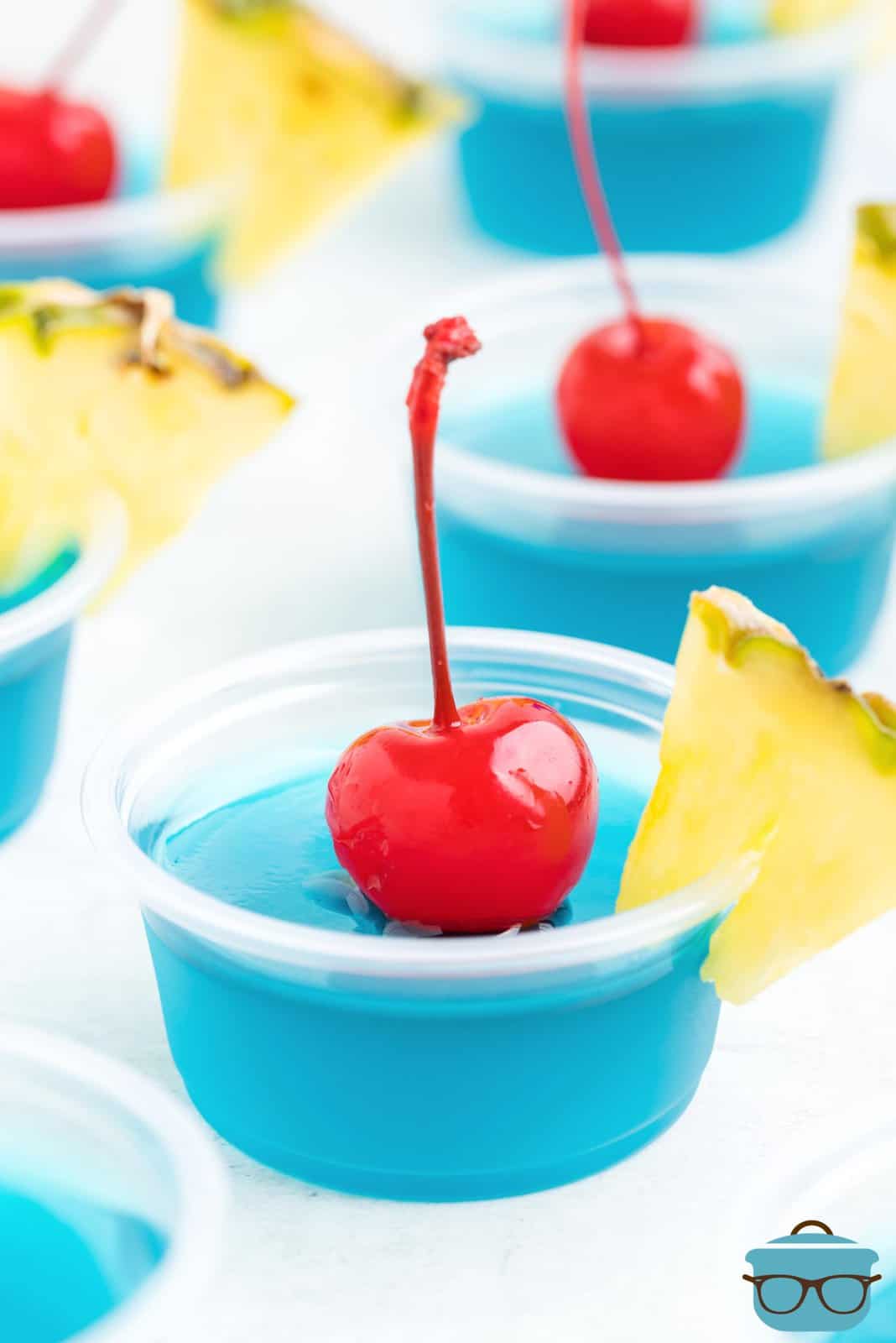A few Blue Hawaii Jello Shots with cherries and pineapple garnishes.