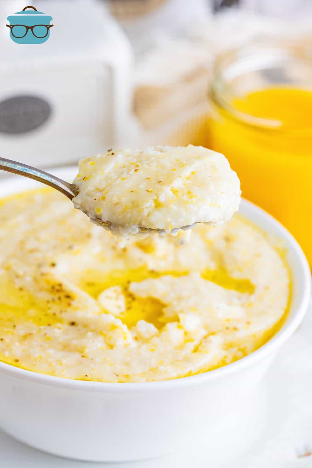 A bowl of southern grits with a spoon holding a bite above it.