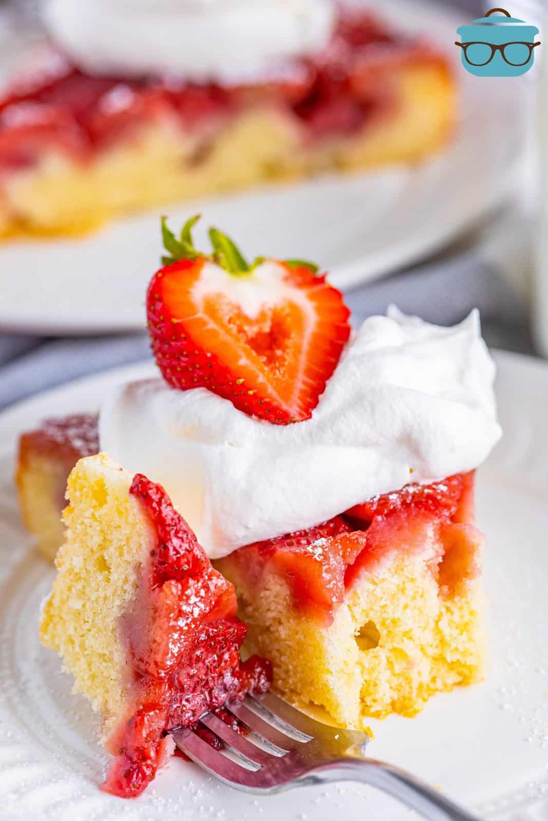 A plate with a piece of Strawberry Upside Down Cake with a fork in it.