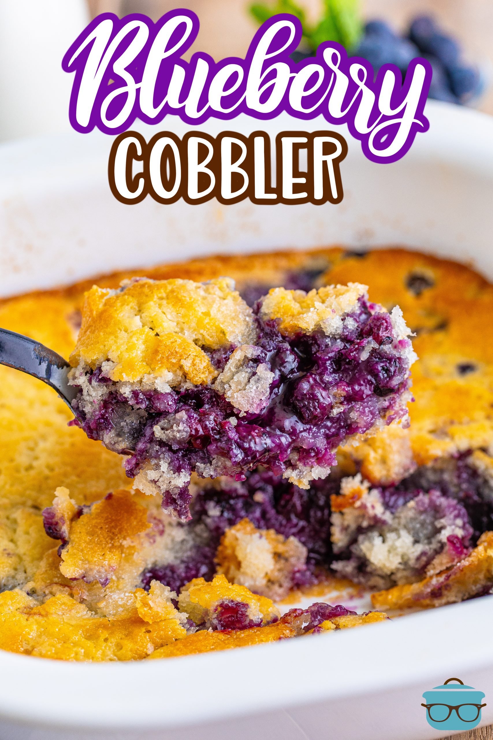 a serving spoon holding up some blueberry cobbler over the baking dish. 