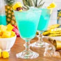 A few Blue Hawaiian Cocktails with garnishes around.