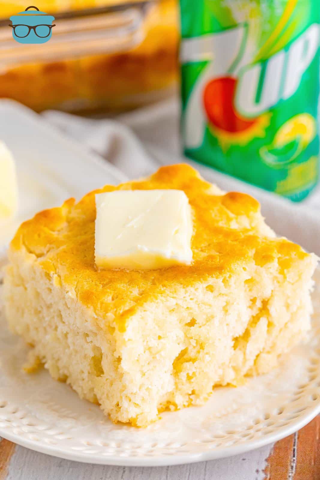 A 7Up Butter Dip Biscuit sitting on a plate with a pad of butter on top.