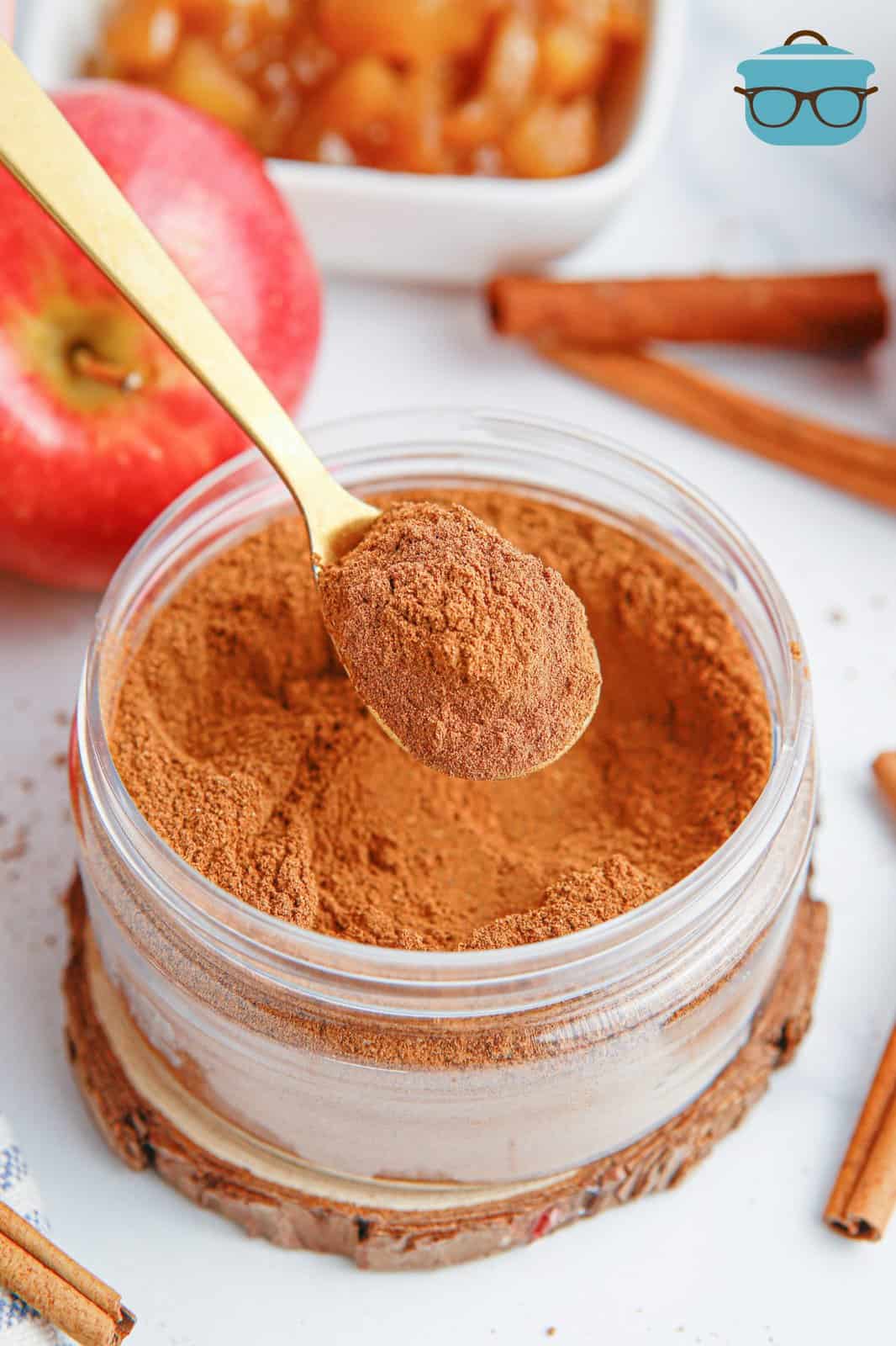 A spoon holding some Apple Pie Spice over the jar.