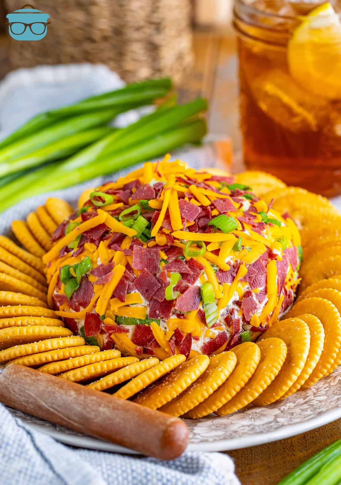 A dried beef cheeseball with crackers around it on a serving plate.