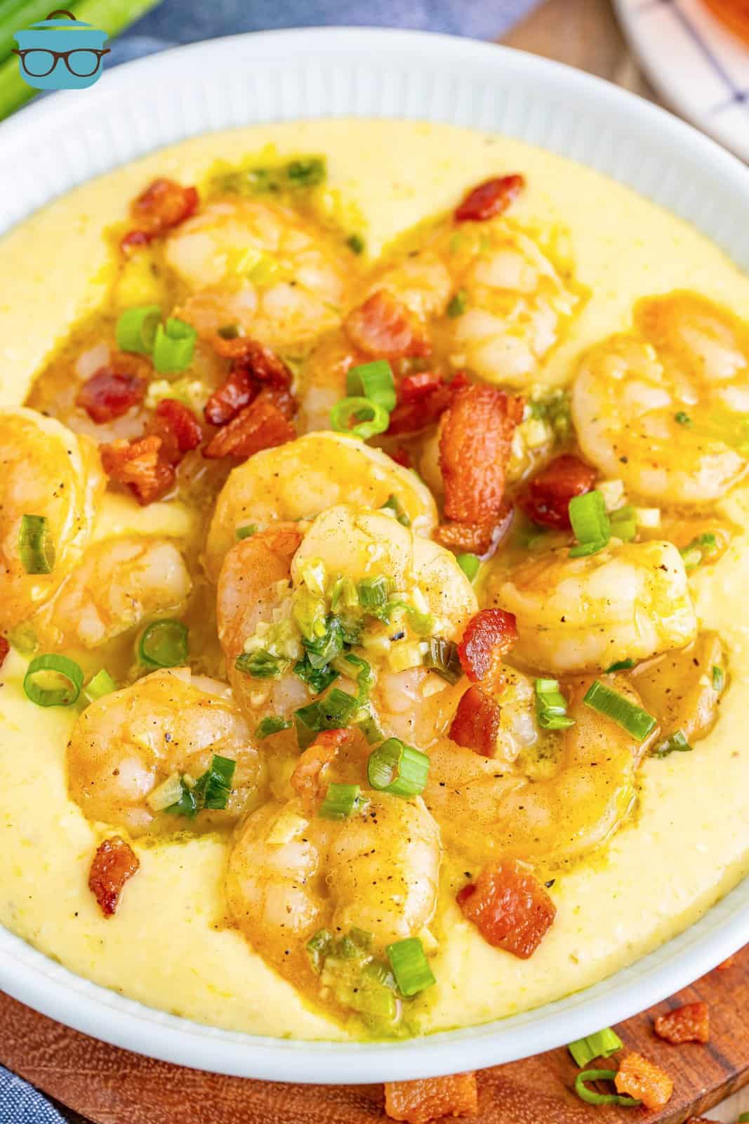 Looking down on a serving bowl of shrimp and grits with garnishes.