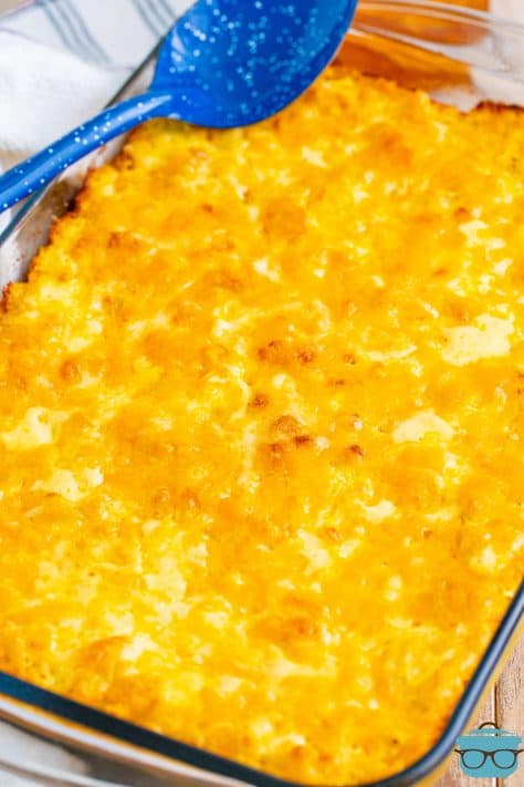 A baking dish with baked mac and cheese and a spoon resting on top.