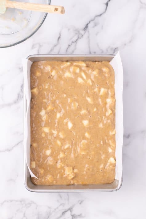A prepared baking pan with chopped apples added to cake batter.