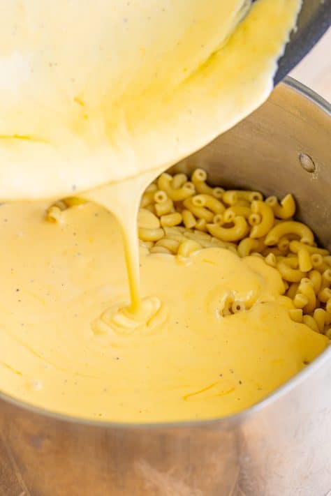Cheese sauce being poured back on the elbow noodles.