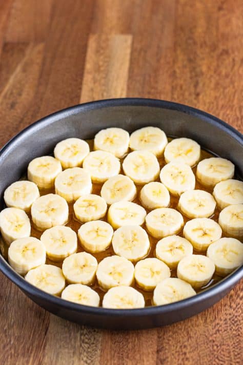 Sliced banana on top of the brown sugar butter mixture in a pan.