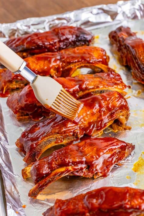 A pastry brush brushing BBQ sauce on the ribs.