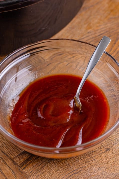 A small mixing bowl with barbecue sauce and water.