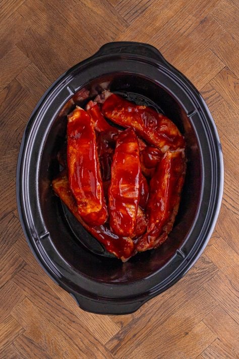 Ribs with seasoning and sauce in a crockpot.