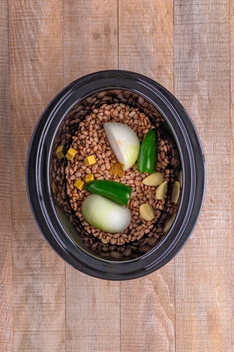 Beans, onion, jalapeno, bouillon, garlic, and cumin in a slow cooker.