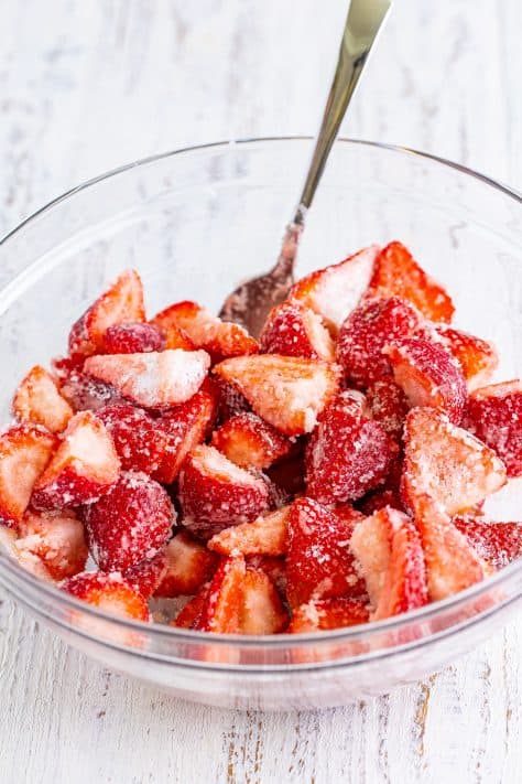 A mixing bowl of cut strawberries coated in the cornstarch, sugar, lemon juice, and vanilla.