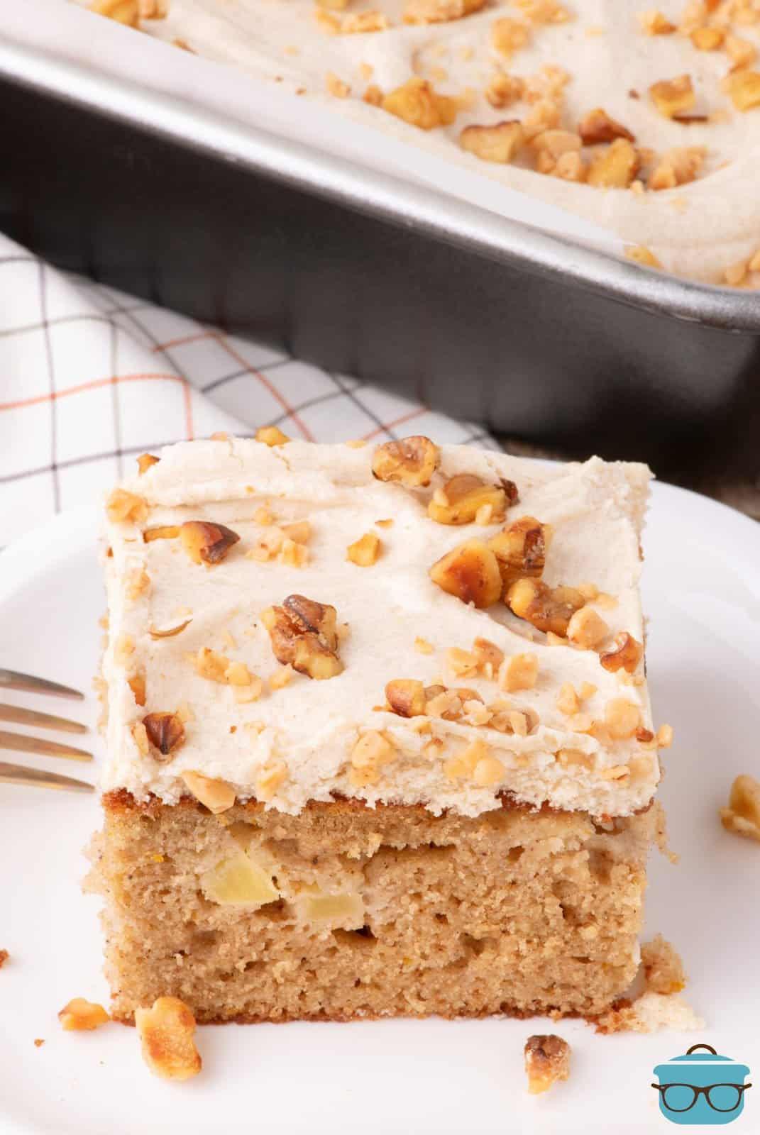 A plate with a slice of Apple Spice Cake with Brown Sugar frosting and fork beside it.