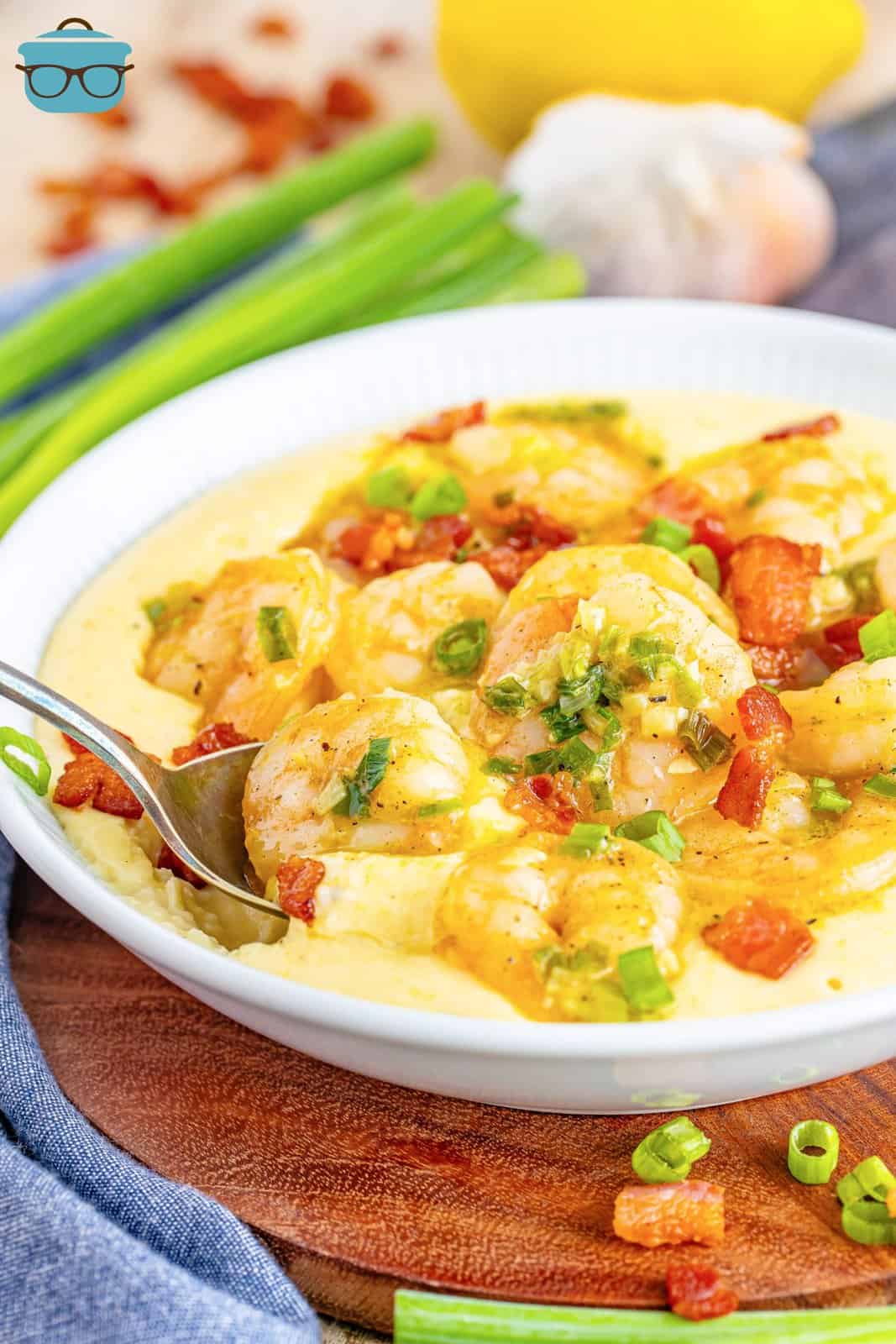 A spoon dipping in a bowl of shrimp and grits.