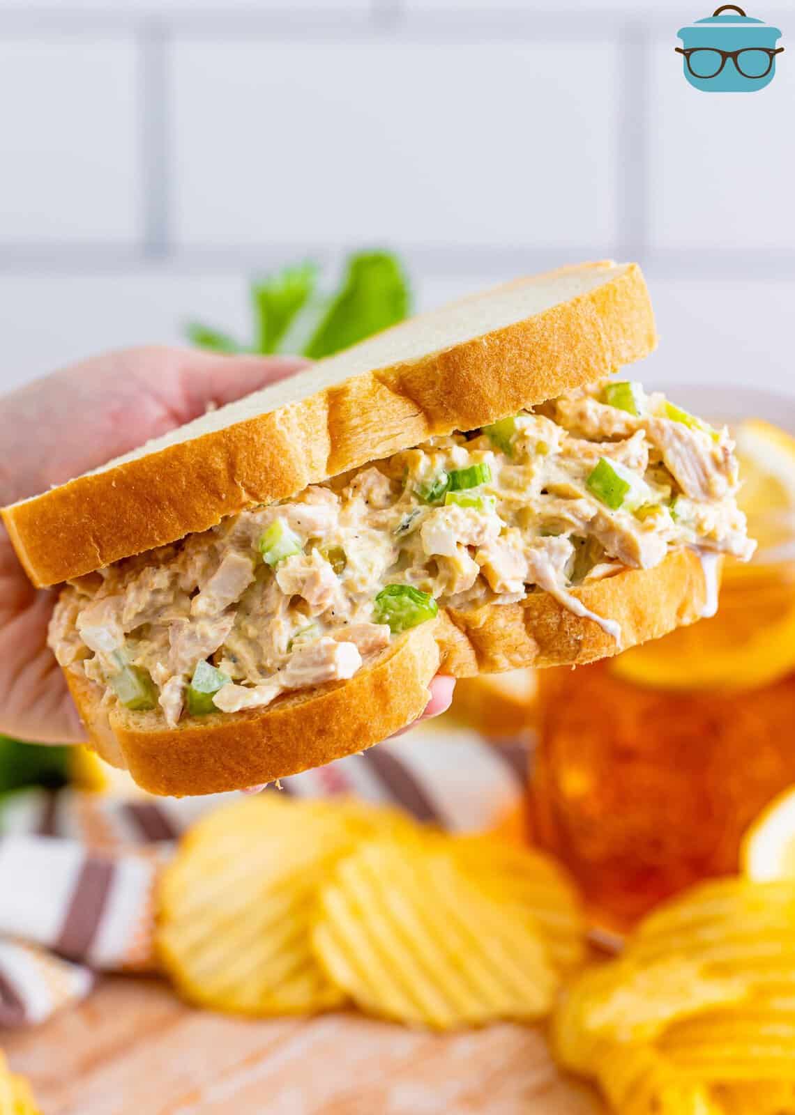A hand holding a tuna salad sandwich.