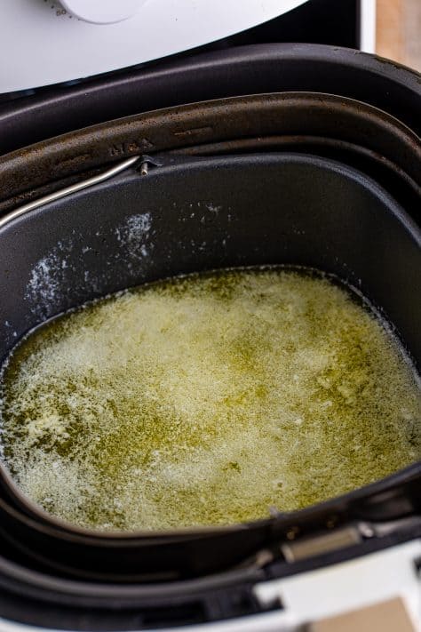 Melted butter in a baking dish in an Air Fryer basket.