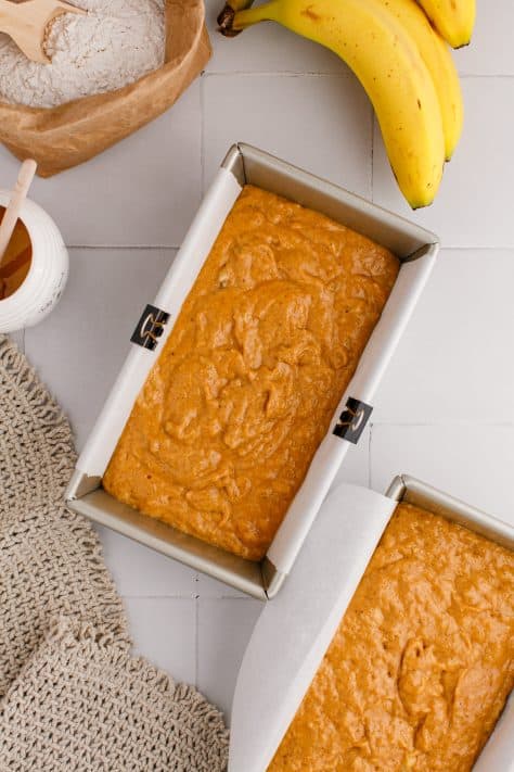Two loaf pans with pumpkin banana bread batter.