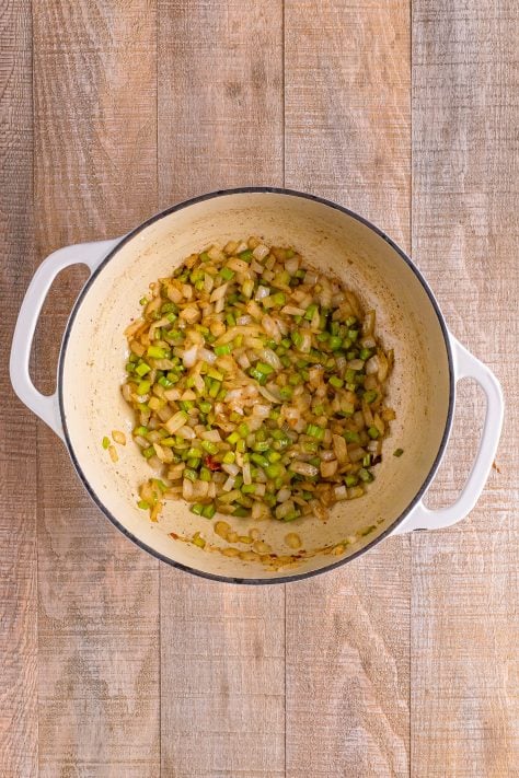 A dutch oven with bacon, celery and onion.