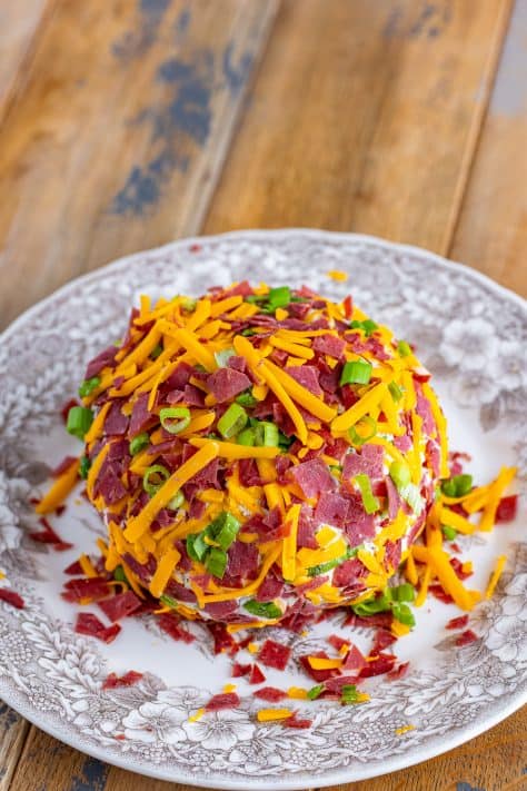 Cheese ball covered in cheese, green onions, and dried beef.