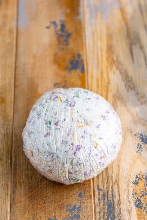 Cheese ball wrapped tightly in plastic wrap.