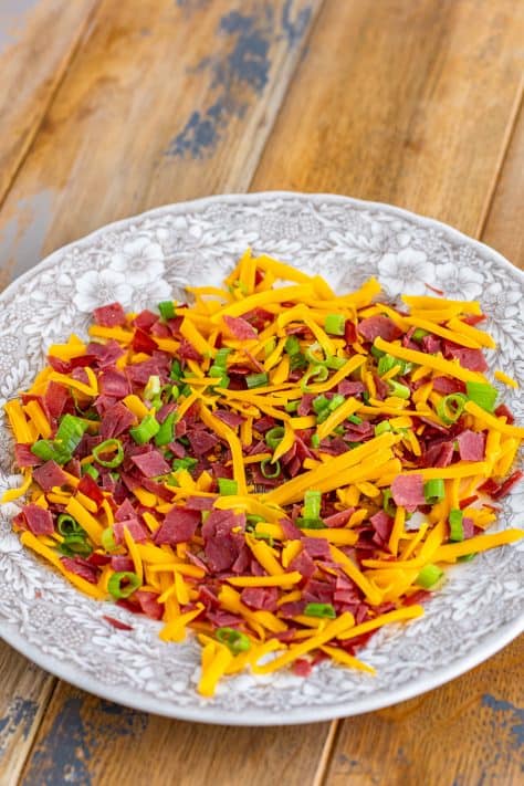 A plate of cheddar cheese, green onions, and dried beef.