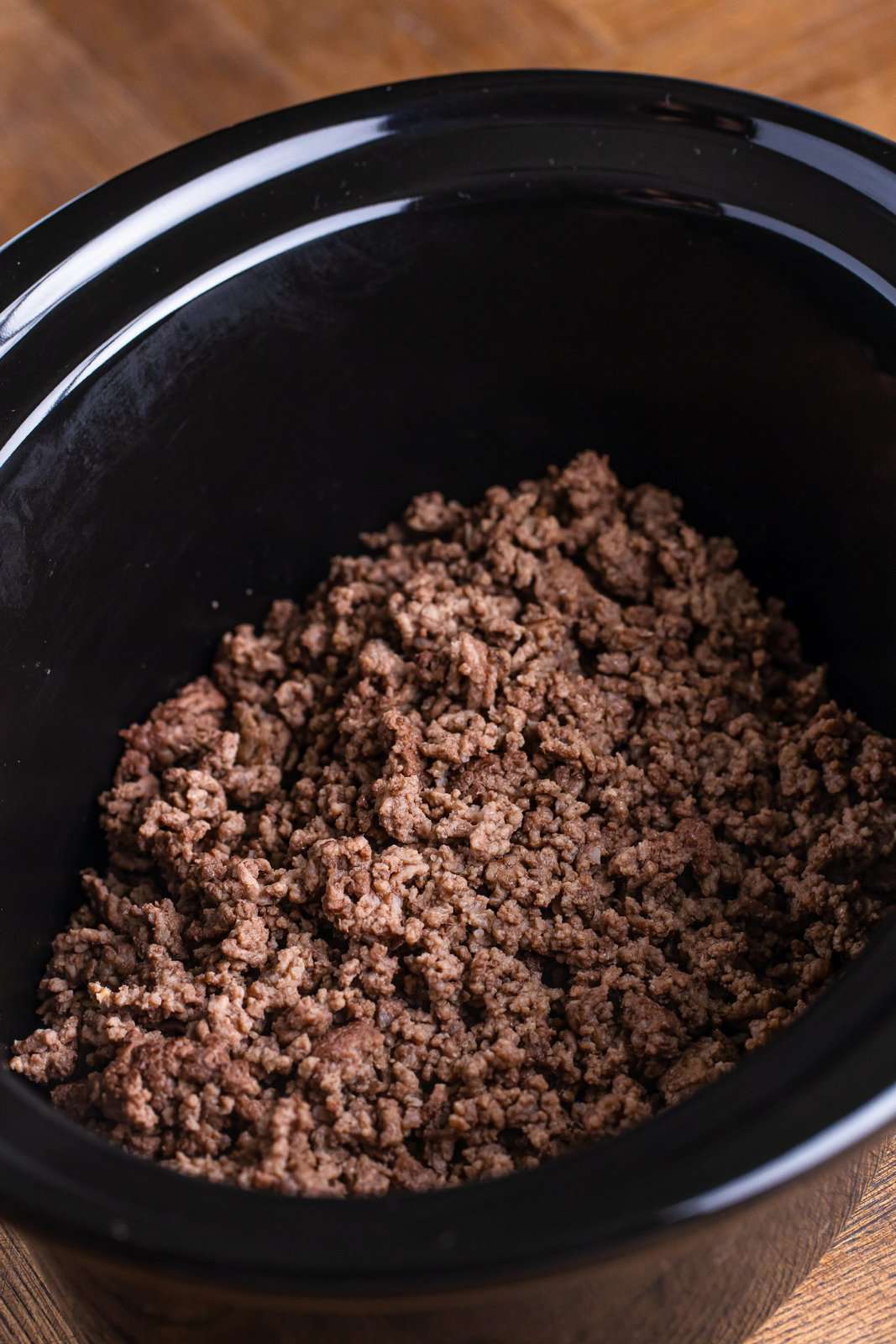 A slow cooker insert filled with ground beef.