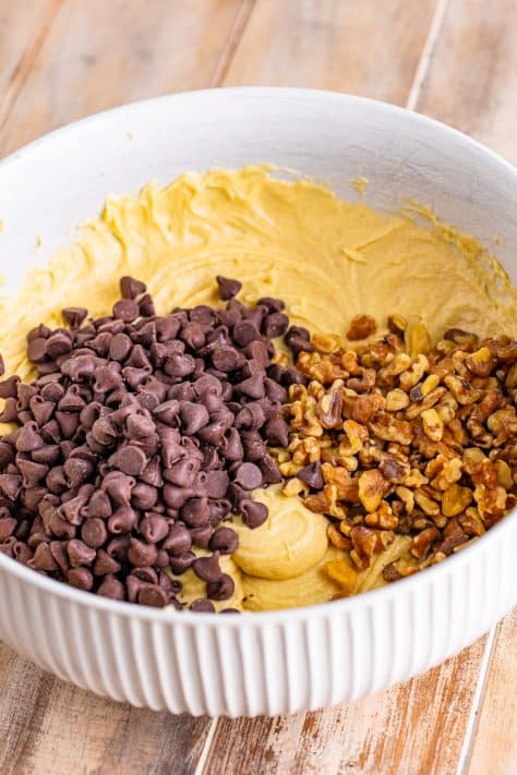 Chocolate chips and walnuts being added to cookie dough.
