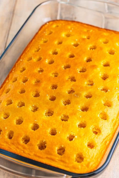 Holes poked into a yellow cake.
