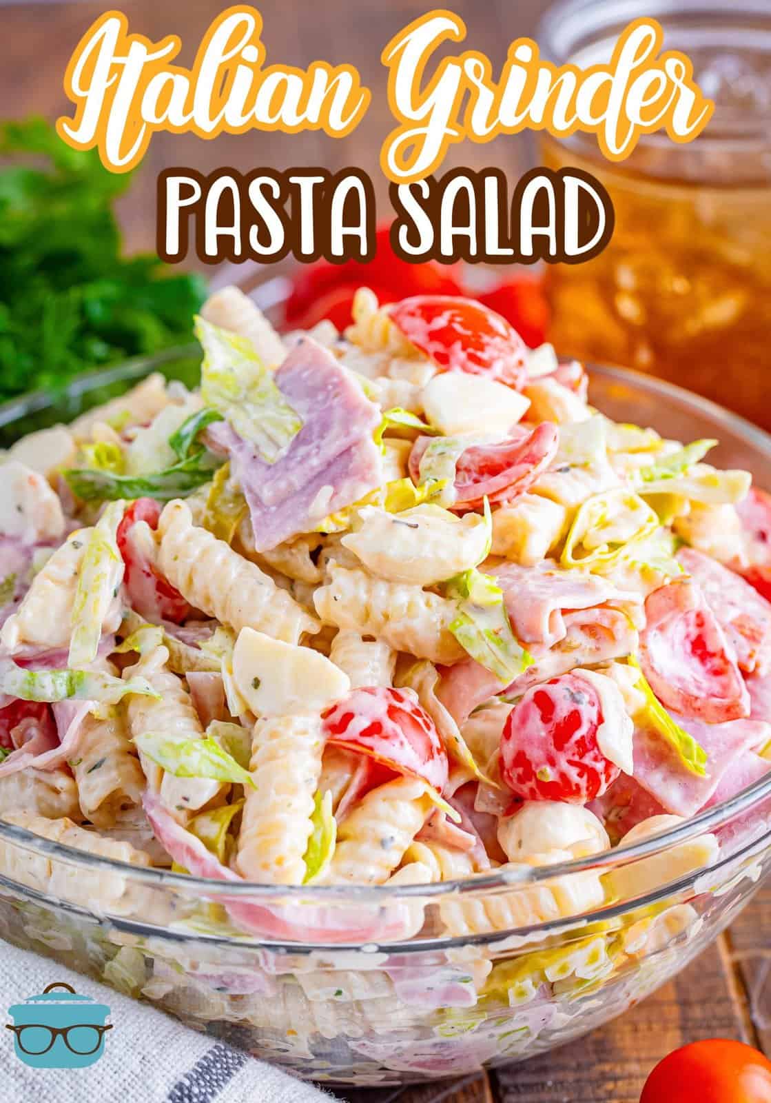A heaping mounds of Italian grinder pasta salad and a glass mixing bowl.