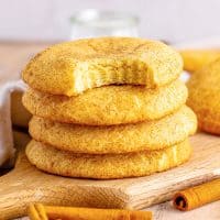 A small stack of Crumbl Snickerdoodles with the top one missing a bite.
