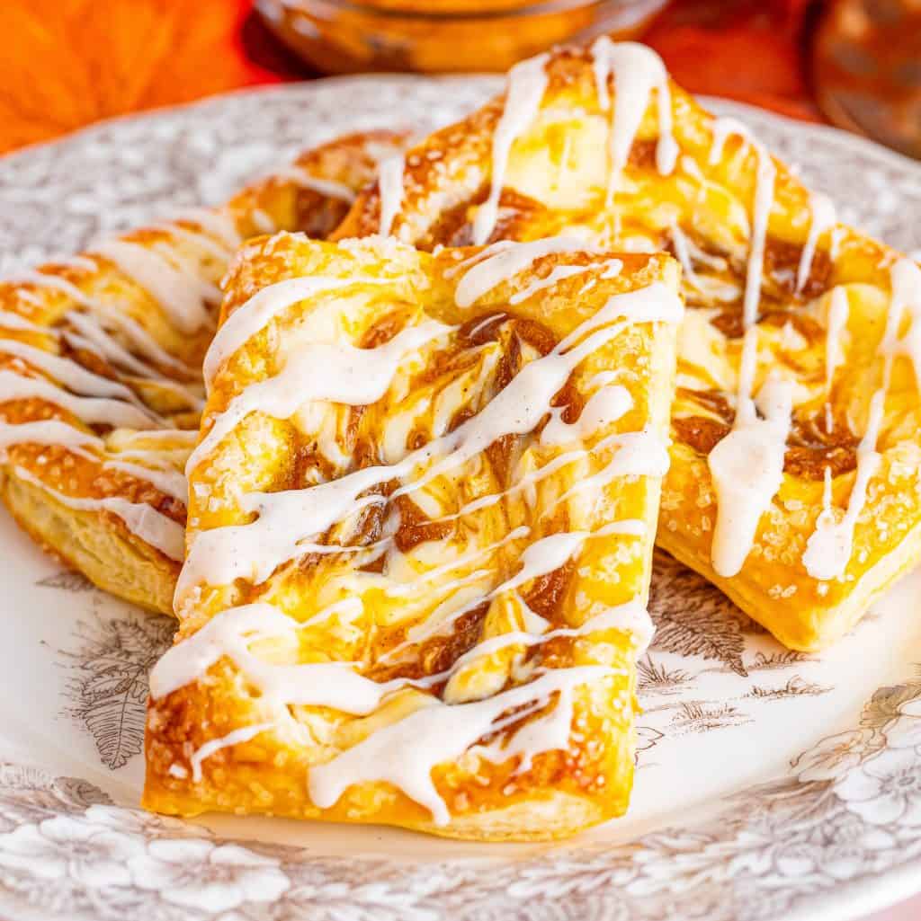 A pile of pumpkin cheesecake danishes on a plate.
