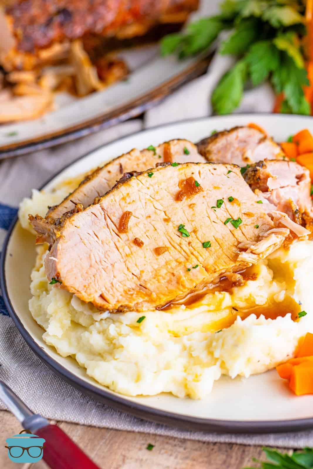 A plate of mashed potatoes with a few slices of Pork Loin.