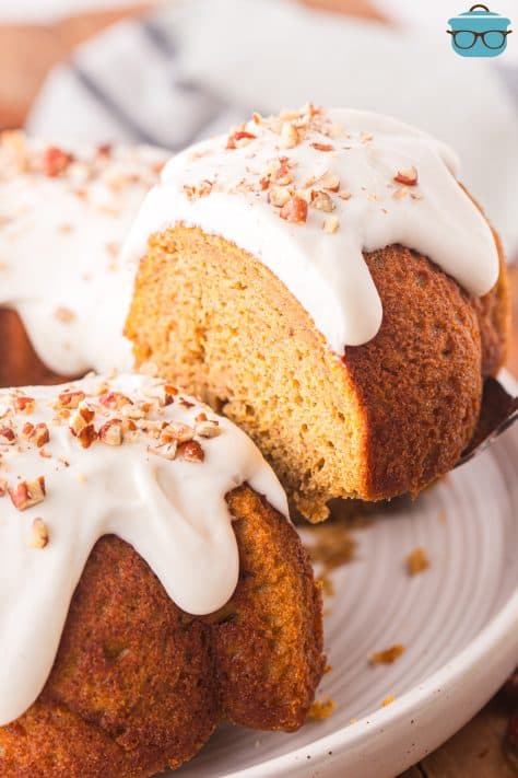 A serving utensil lifting is Lisa pumpkin Bundt cake from the rest of the cake.